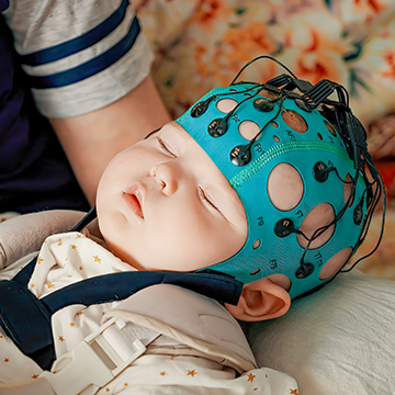 Baby participating in study with hat on that measures brain activity