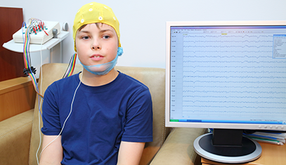 Child with wires on head and monitor with data